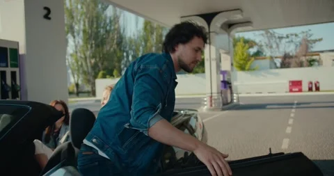 A curly brunette guy in a denim jacket gets out of a gray convertible and Stock Footage 245828218