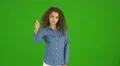 The curly businesswoman thumb down and stand on the green background. Real time 4k or 4k+ Resolution