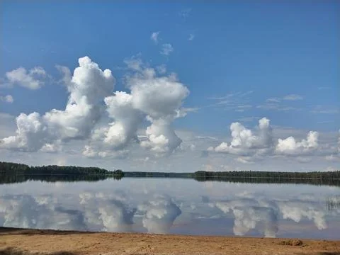 Curly clouds reflected in the lake surface Foto stock