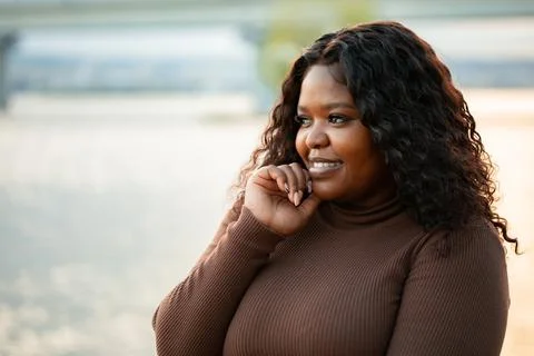 Curly cute dark-haired smiling, pleasant and modern African American woman near Stock Photos