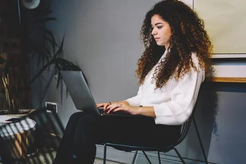 Curly female programmer checking software text during laptop working on distance Stock Photos