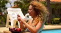 Curly Funny Woman Receiving Message and Laughing in a Pool. HD Footage