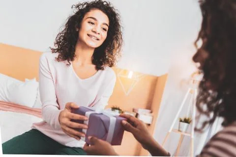 Curly girl feeling curious while opening surprise Stock Photos