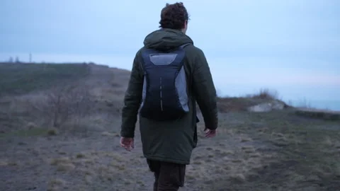 Curly guy with backpack lonely walks a desert coast in late autumn Stock Footage 151655028