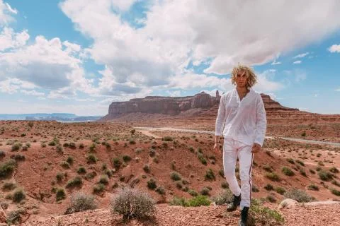 A curly haired blonde man posing around the famous Buttes of Monument Valley  Foto stock