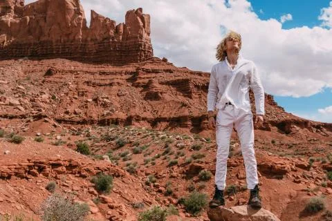 A curly haired blonde man posing around the famous Buttes of Monument Valley  Stock Photos