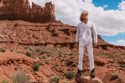 A curly haired blonde man posing around the famous Buttes of Monument Valley  Foto stock