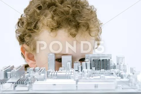 Curly Haired Boy Hiding Behind And Looking Through Circuit Board
