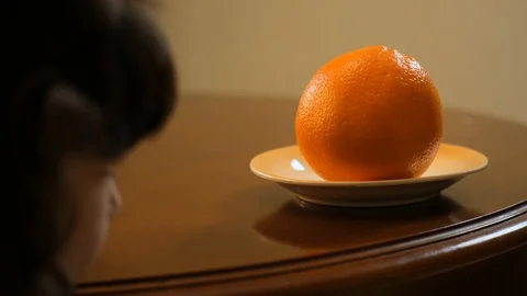 Curly-haired boy takes an orange from the table. Healthy food Stock Footage 125706678