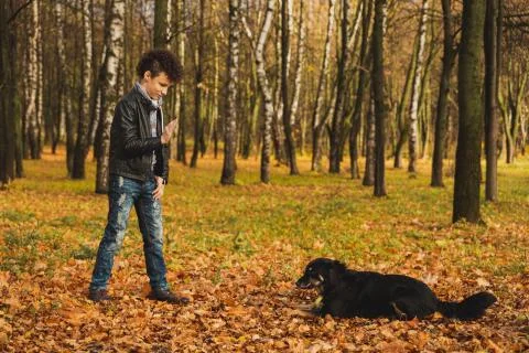 A curly-haired brown-haired boy with a mohawk hairstyle in a leather jacket o Stock Photos