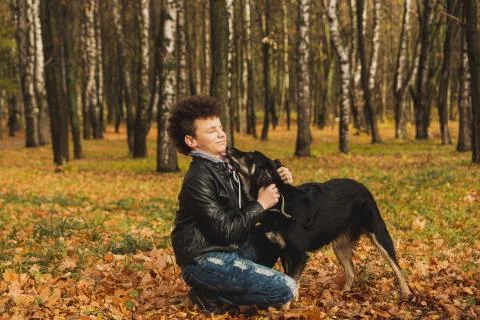 A curly-haired brown-haired boy with a mohawk hairstyle in a leather jacket o Stock Photos