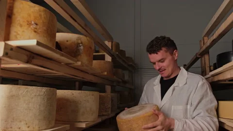 Curly-haired cheese maker checks the maturation of parmesan 库存影片 180041661