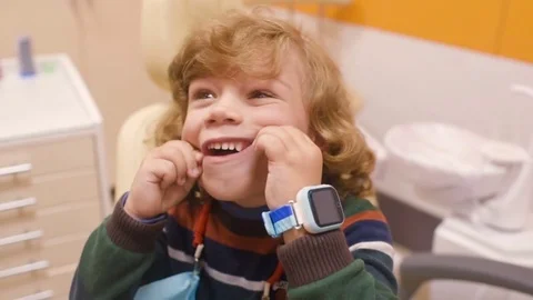 Curly-haired child indulges and grimaces in a dental chair Stock Footage 84786398