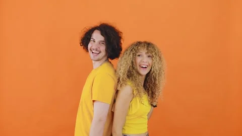 Curly-haired couple standing back-to-back yellow background Stock Footage 297226672