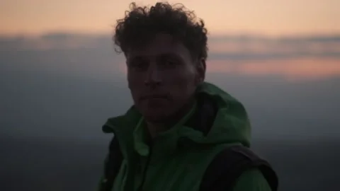 Curly-haired guy looks into the camera at sunset Stock Footage 171636780