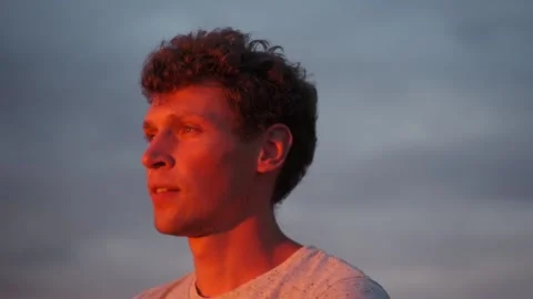 Curly-haired guy looks at the setting sun Stock Footage 172089793