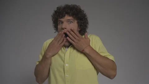Curly-haired guy portrays a shock. Young man in the studio on an isolated Stock Footage 139464338