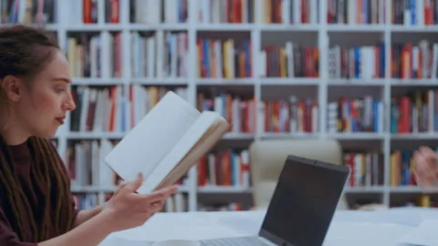 Curly-Haired Guy Sharing a Textbook with Dreadlocked Girl During a Library Study Vídeo Stock 335126982