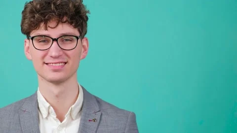 Curly haired handsome young man that is putting on eye glasses and smiling Stock Footage 152845328