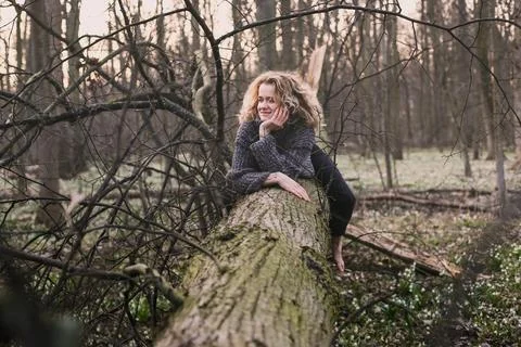 Curly haired lady resting on tree trunk scenic photography Stock Photos