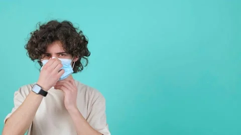 Curly haired man puts a mask on his face from air pollution and coronavirus. Stock Footage 151480718