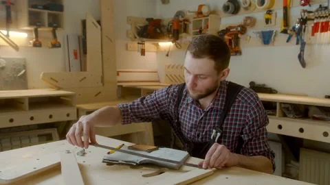 Curly joiner master using smartphone checks measurements , handsome Caucasian Stock Footage 150877467