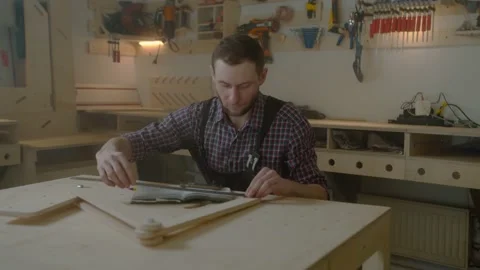 Curly joiner master using smartphone checks measurements , handsome Caucasian Stock Footage 150877568