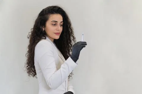 With curly locks cascading, the esthetician evaluates the syringe in her hand Stock Photos