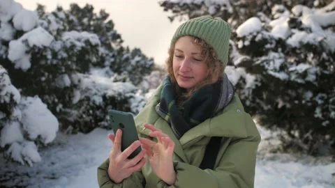 Curly Woman browsing internet using phone outdoor.Girl holding phone and surfing Stock Footage 225934250