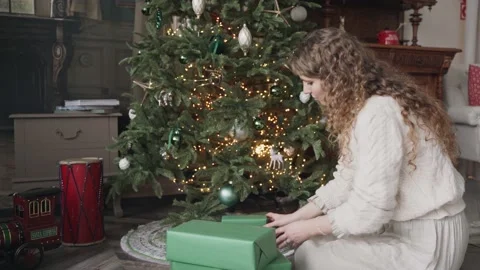 Curly woman puts gifts under the Christmas tree Stock Footage