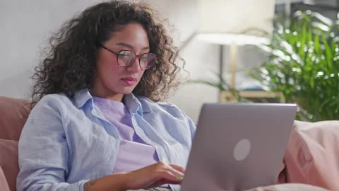 Curly woman using laptop checking email news online sitting on sofa, searching Stock Footage 205851137