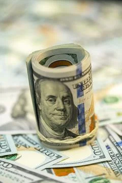 Currency rolled into a bundle atop scattered dollar bills Stock Photos