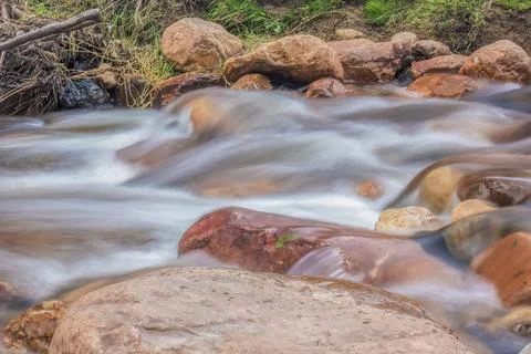 The current of a river flowing over rocks and stones Stock Photos