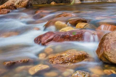 The current of a river flowing over rocks and stones Stock Photos