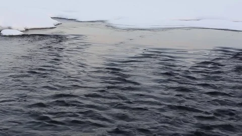 Current of water in the river in the winter among snow on the Sunset Stock Footage 73685407