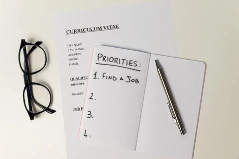 Curriculum vitae and notebook with text "priorities, find a job".  Stock Photos
