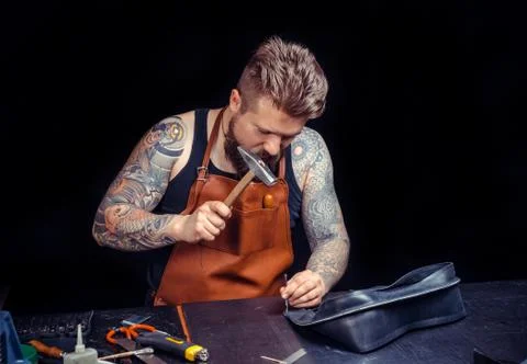 Currier of leather processing a leather workpiece at his workshop Stock-Fotos