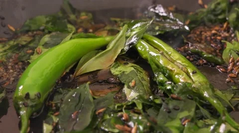 Curry leaves being thrown in a pan with spices, chillies and condiments Stock Footage 62828635