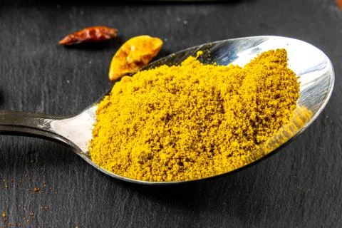 Curry in spoon on stone background 스톡 사진