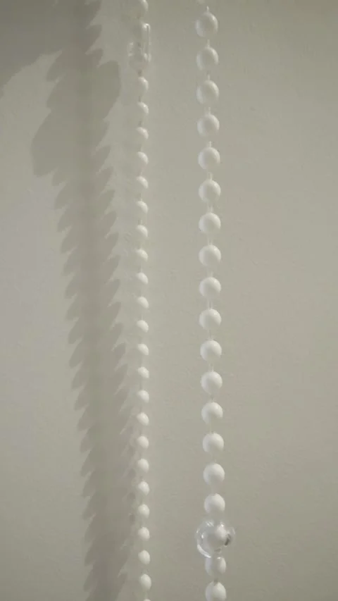 Curtain Blind Bead Chain Casting Soft Shadow on Minimal White Wall Stock Footage 329906640