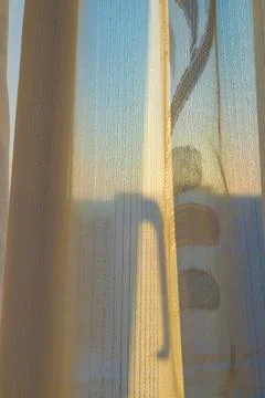 Curtain on a window in the rays of the sun. Stock Photos
