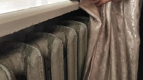 The curtains open and the old heating radiator becomes visible. Heating in the Stock Footage 325290788