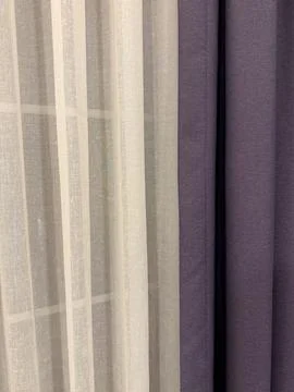 Curtains with sheer and solid fabrics in neutral and purple tones create a .. 库存照片