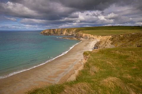 Curved beach surrounded by cliffs with powerful clouds . Kilfarrasy Beach. Co Stock Photos
