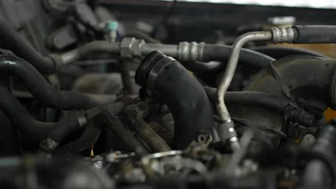 A curved black rubber air intake hose is secured with a clamp amid various pi Stock Footage 345110227