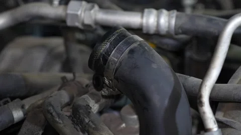 A curved black rubber coolant or air intake hose is secured with a metal clam Stock Footage 345107631