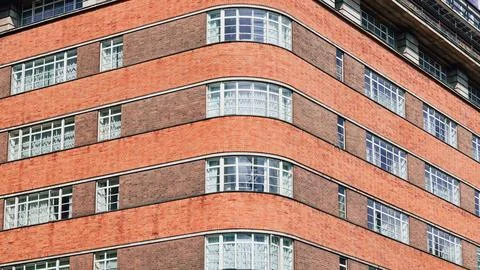 Curved brick building facade with large windows and decorative elements 스톡 사진