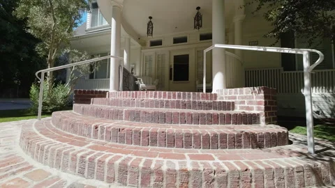 Curved brick front steps with white railings on a porch Stock Footage 345703365