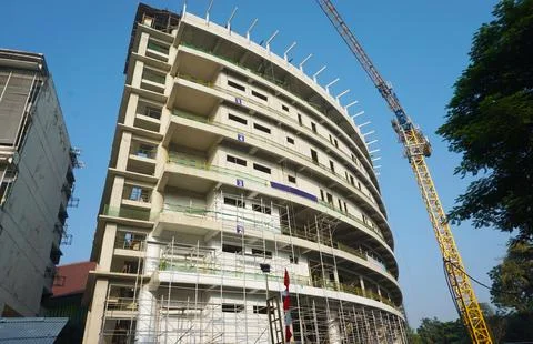 Curved building construcion facade in progress with tall crane Stock Photos