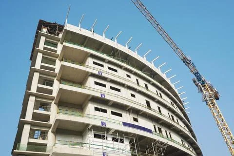 Curved building construcion facade in progress with tall crane Stock Photos